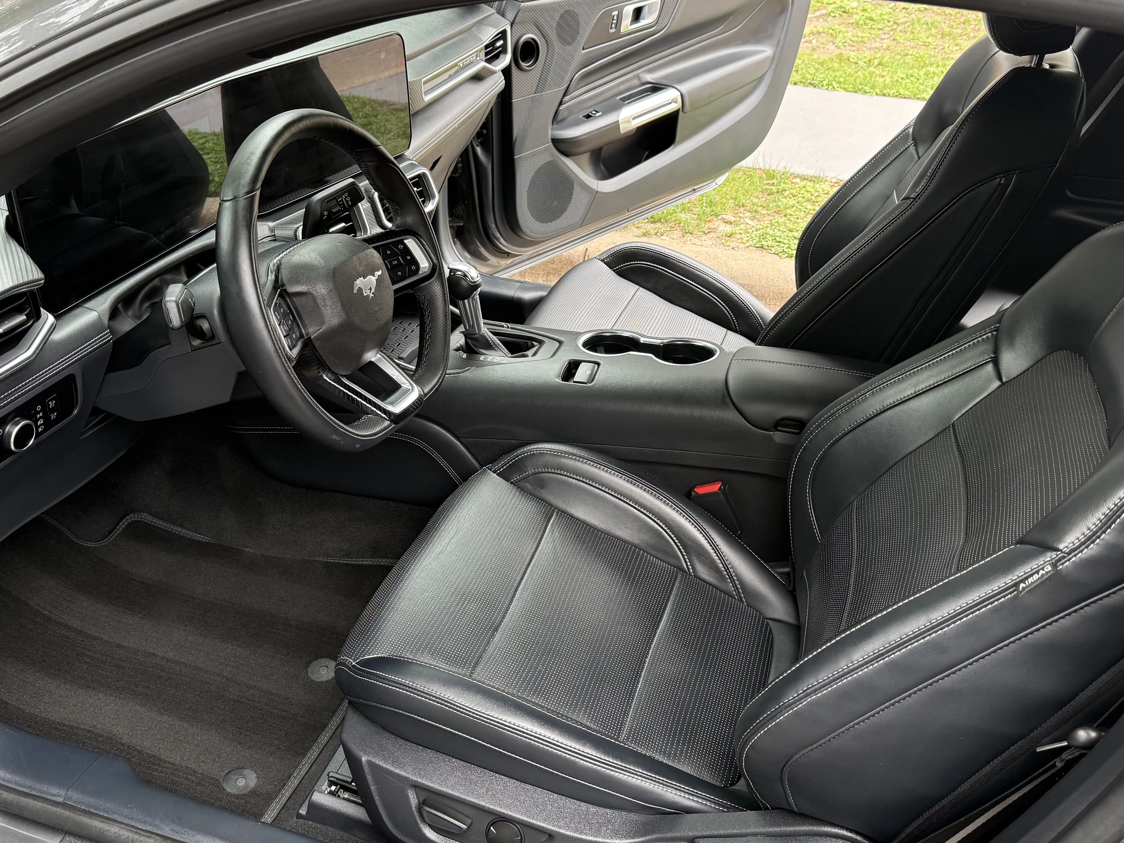 Modern Ford Mustang interior with black leather seats, digital dashboard, and leather steering wheel.